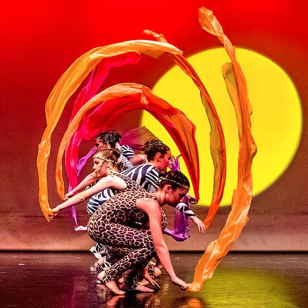 dance show photography of dancers performing with ribbons of material making an arch with sunrise background