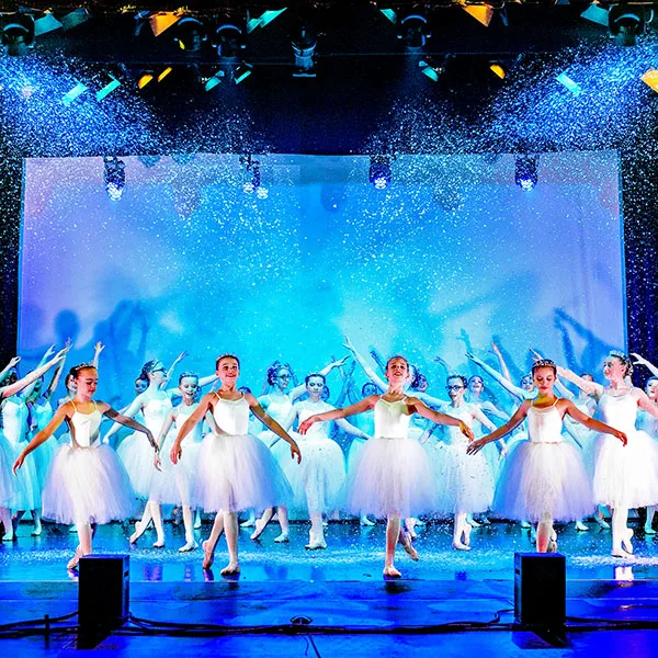 dancers on stage in white ballet costumes with snow effect on stage - dance show photography