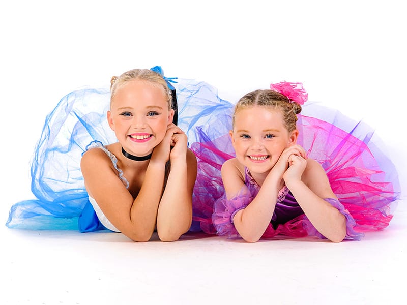 young dance girls in brightly coloured tutus smiling at camera