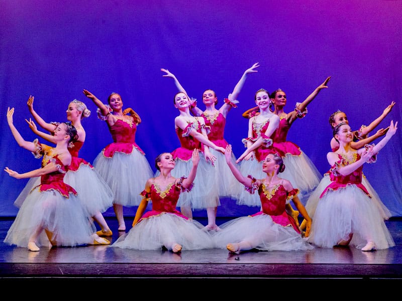 young ballet dancers in romantic tutus pose at end of performance
