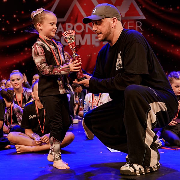 judge presents trophy to young girl dancer