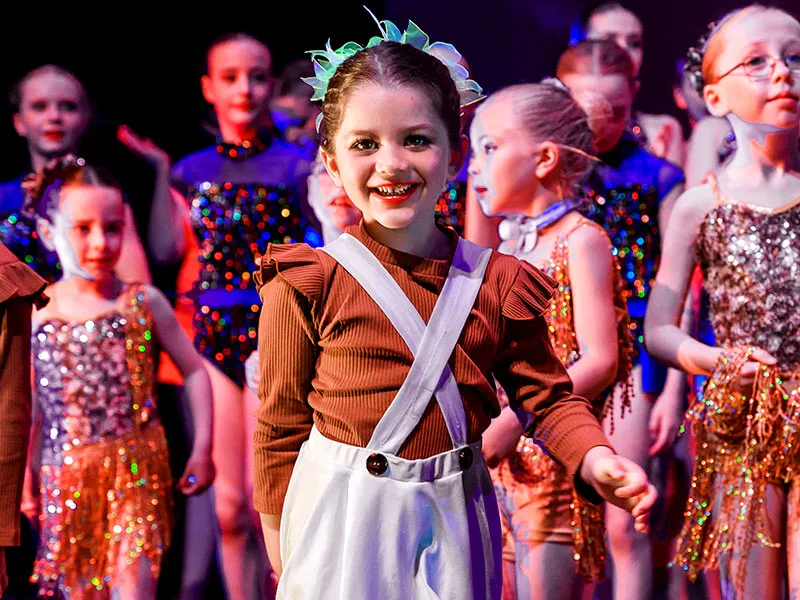 close cropped photo at end of dance school show features girl in costume smiling at camera