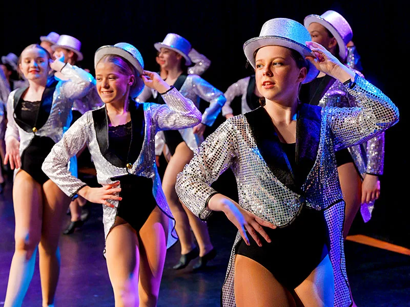 close cropped dance show photo showing girls in sparkly costumes smiling
